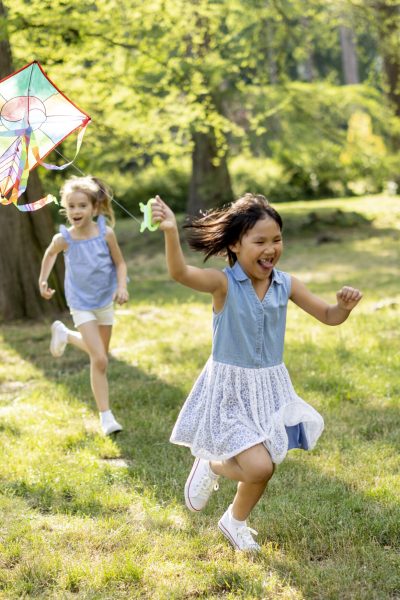 Little Asian girl running happily with a kite in the park